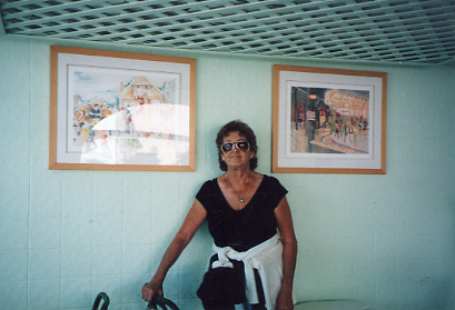 Susan standing in front of two of her watercolors in the coffie shop on Dudley